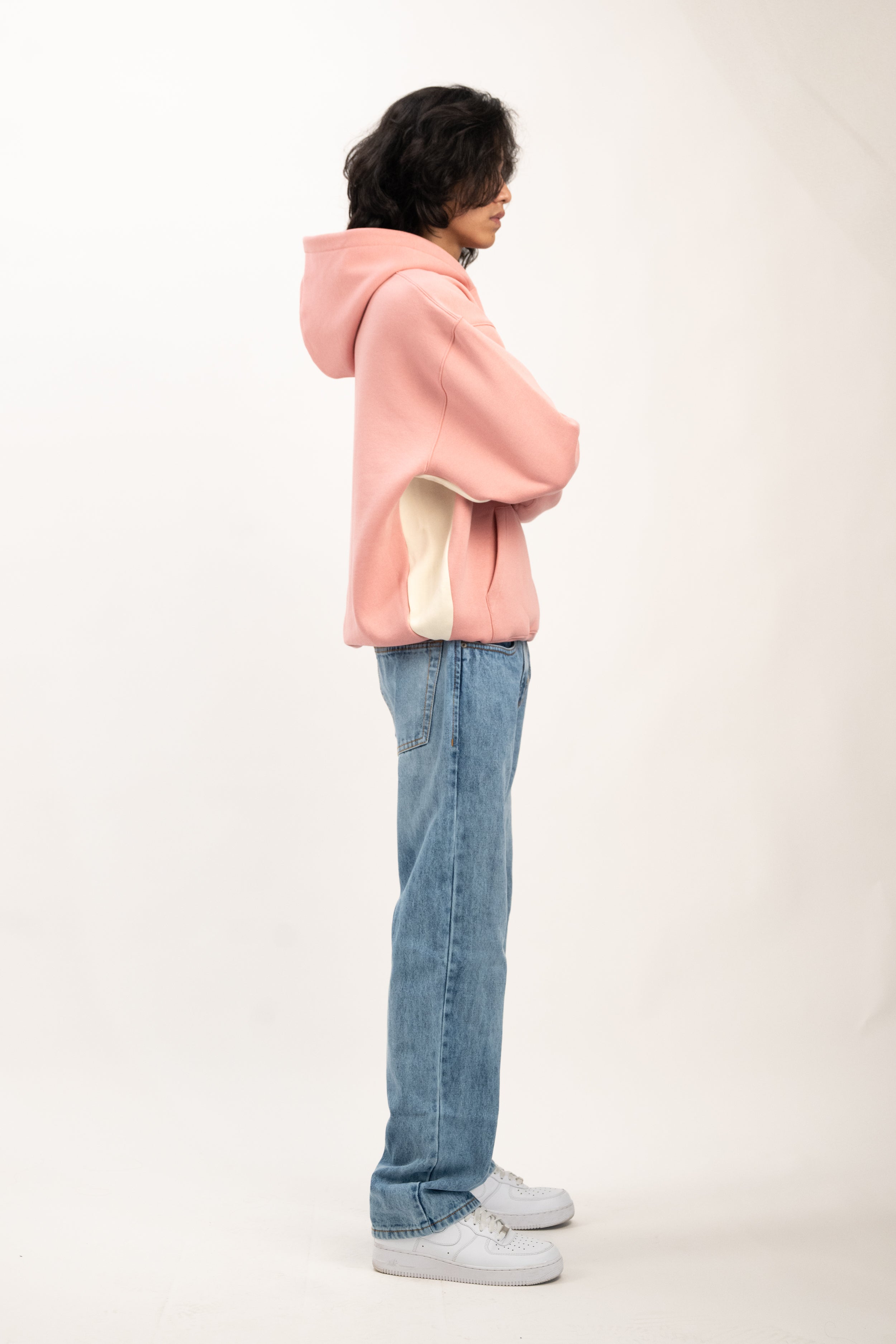 Person wearing a pink hoodie and blue jeans on a white background